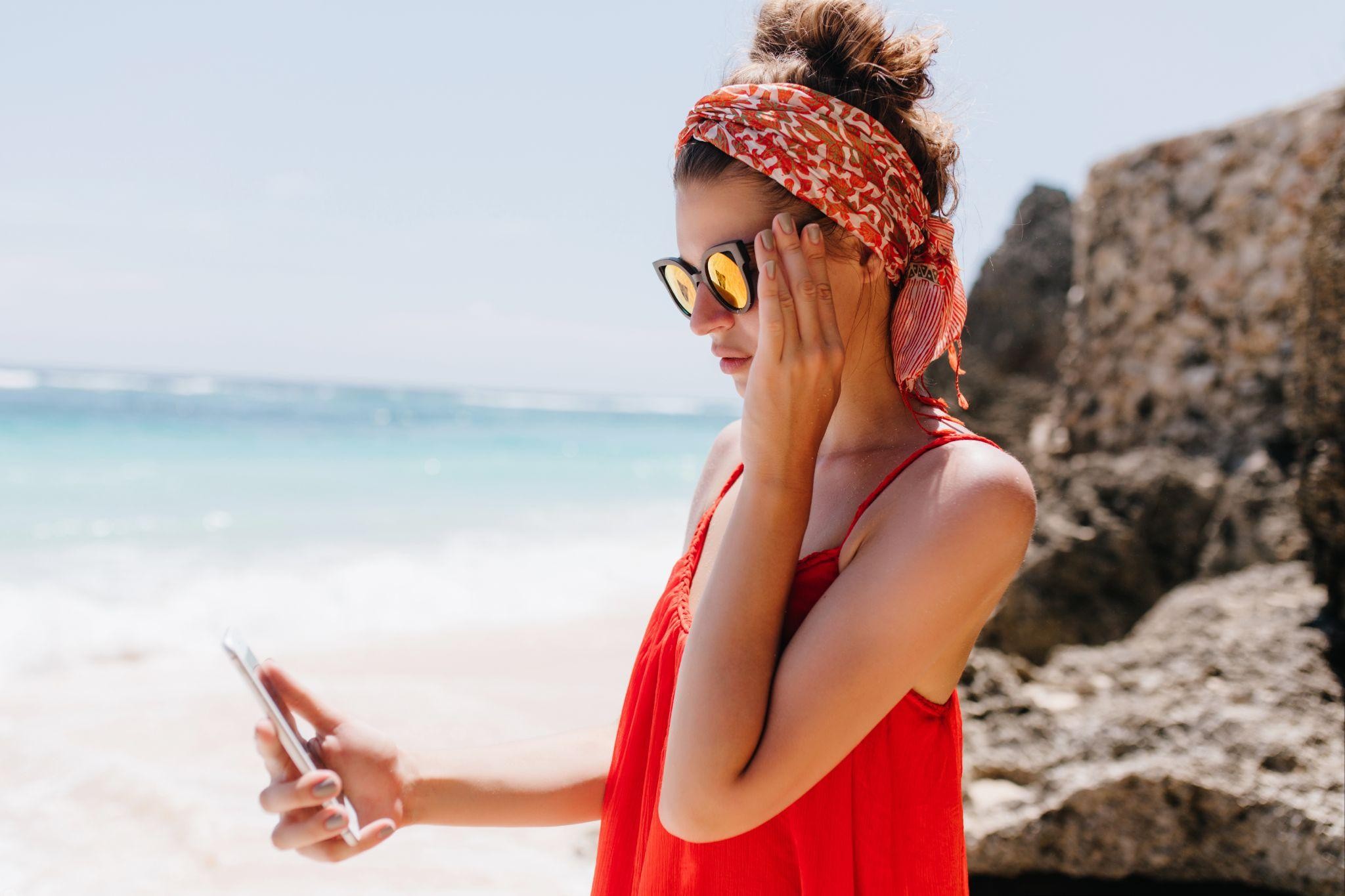 Woman standing near rocks with smartphone